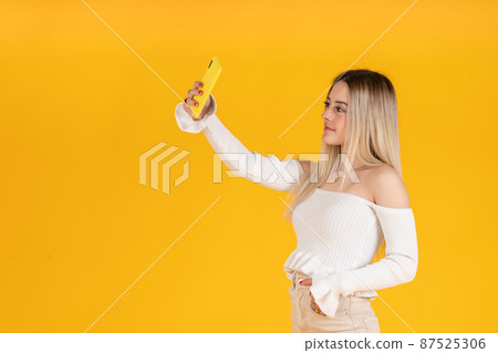 young woman taking a selfie with her smartphone. Studio photography young woman taking a selfie with her smartphone. Studio photography 87525306