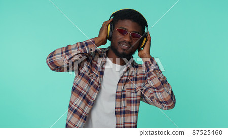 Cheerful attractive man listening music via headphones and dancing disco fooling around having fun 87525460