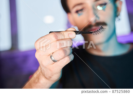 Caucasian man looking at the brush and preparing creating new make up at his face Caucasian man looking at the brush and preparing creating new make up at his face 87525860