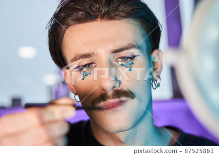 Man looking at the brush for make up and preparing creating new look at his face 87525861