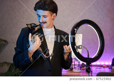 Brunette man with mustaches looking at his lovely dog and shooting together at the smartphone Brunette man with mustaches looking at his lovely dog and shooting together at the smartphone 87525902