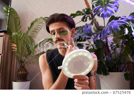 Handsome man massage his face, making lifting facial procedure, using jade scraper 87525976
