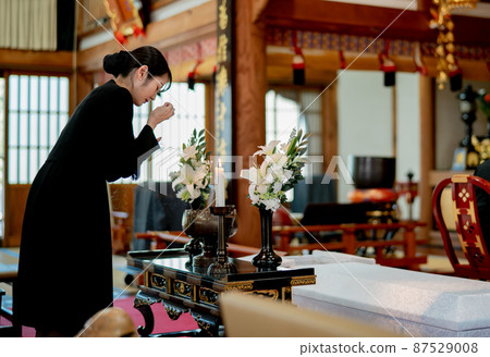 A woman standing on an incense stand at a funeral (incense) 87529008