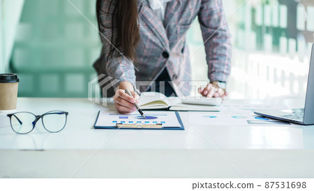 Close up a Business woman using calculator and laptop for doing math finance on a wooden desk, tax, accounting, statistics, and analytical research concept. Close up a Business woman using calculator and laptop for doing math finance on a wooden desk, tax, accounting, statistics, and analytical research concept. 87531698
