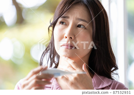 一個穿著房間的女人,當她看到手裡的溫度計時,她看起來很消極 一個穿著房間的女人,當她看到手裡的溫度計時,她看起來很消極 87532931
