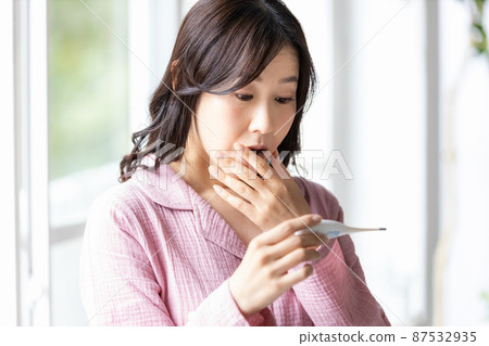 一個穿著房間的女人,當她看到手裡的溫度計時,她看起來很消極 一個穿著房間的女人,當她看到手裡的溫度計時,她看起來很消極 87532935