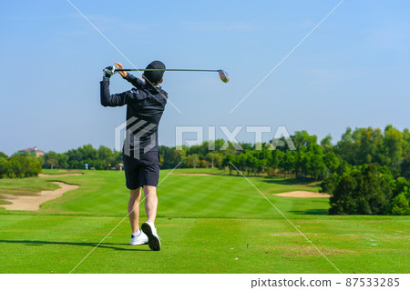 Man Golfer Hitting Ball with Club on Beatuiful Golf Course 87533285