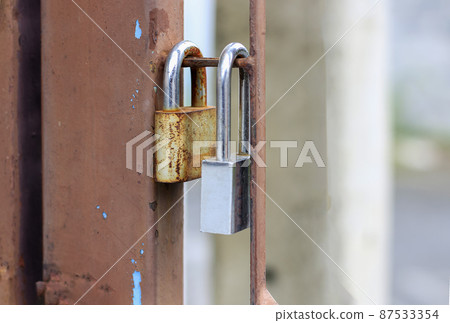 Two padlocks on the old and rusted iron dash. 87533354