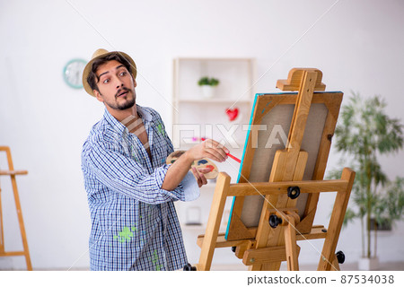 Young man enjoying painting at the studio Young man enjoying painting at the studio 87534038