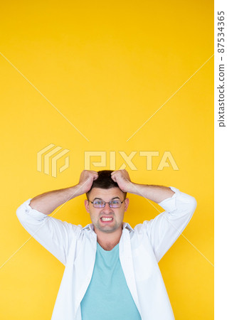 Difficult problem. Overload man. Desperate feelings. Shocked outrage guy grasping hair with hands meeting unexpected situation isolated yellow. 87534365