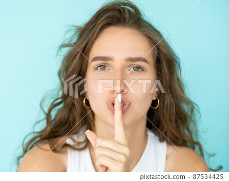 Shush finger. Female portrait. Mute expression. Pretty beautiful woman showing gesture for keeping secret isolated blue. Shush finger. Female portrait. Mute expression. Pretty beautiful woman showing gesture for keeping secret isolated blue. 87534425