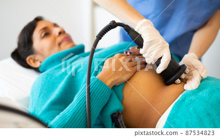 Woman receiving radio frequency abdomen lifting procedure Woman receiving radio frequency abdomen lifting procedure 87534823
