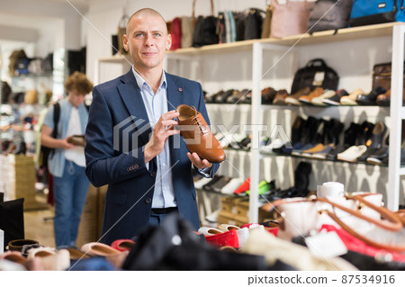 Smiling man looking for classic shoes in shoe store 87534916