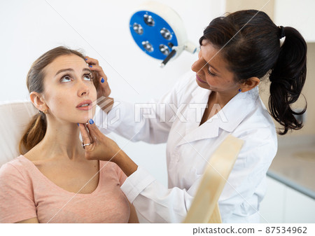 Beautician examining face skin of female patient 87534962