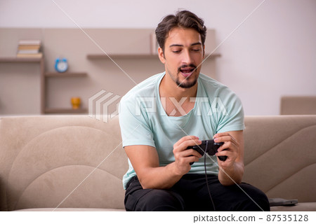 Young man playing joystick games at home Young man playing joystick games at home 87535128