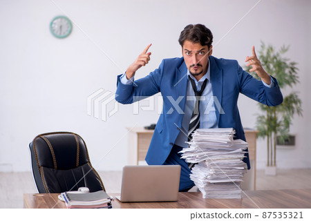 Young male employee unhappy with excessive work in the office 87535321