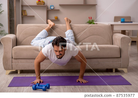 Young man doing sport exercises at home 87535977