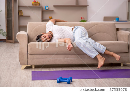Young man doing sport exercises at home 87535978