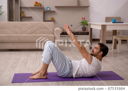 Young man doing sport exercises at home 87535984