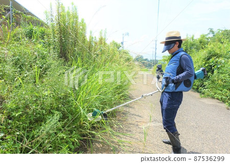 Weeding work along the road, a man mowing grass 87536299