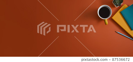 Horizontal photo of creative workplace with notebooks, coffee cup and succulent plants on orange background. Horizontal photo of creative workplace with notebooks, coffee cup and succulent plants on orange background. 87536672