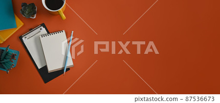 Top view notepad, clipboard, coffee cup and stationery on orange background with copy space. Top view notepad, clipboard, coffee cup and stationery on orange background with copy space. 87536673
