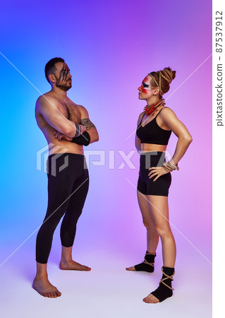 Beautiful young acrobats or gymnasts with colorful face painting on pink blue gradient background. Professional ballet couple dancing, Emotional duet performing choreographic art. Animal instinct Beautiful young acrobats or gymnasts with colorful face painting on pink blue gradient background. Professional ballet couple dancing, Emotional duet performing choreographic art. Animal instinct 87537912