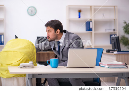 Young male employee looking after new born at workplace 87539204