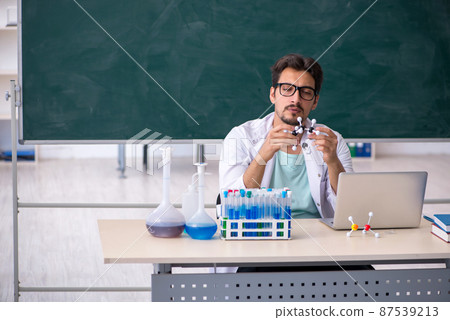 Young male chemist in front of blackboard Young male chemist in front of blackboard 87539213