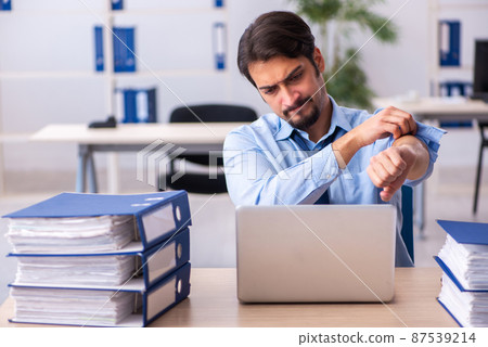 Young male employee and too much work in the office Young male employee and too much work in the office 87539214