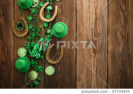 St Patricks Day border of shamrocks beads and coins over a rustic wood background 87539443