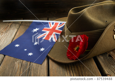 Anzac army slouch hat with Australian Flag and Poppy on wooden background 87539488