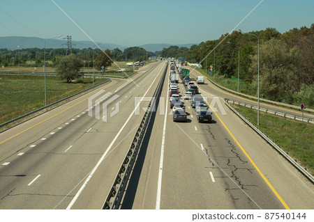 One-way traffic jam on the expressway. Traffic jam on the highway. Blue sky and mountains in the background. One-way traffic jam on the expressway. Traffic jam on the highway. Blue sky and mountains in the background. 87540144