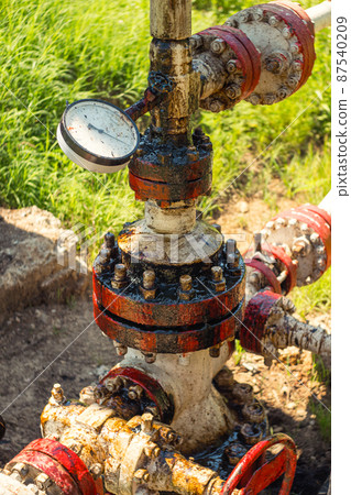 The place where the oil rig is pumping oil pressure gauge, pipes and flanges are stained with oil. Dirty extraction of black gold from the well. The concept of ecology. The place where the oil rig is pumping oil pressure gauge, pipes and flanges are stained with oil. Dirty extraction of black gold from the well. The concept of ecology. 87540209