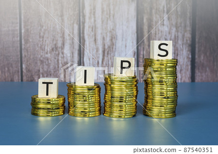 Tips text on wooden block cube on gold coins. Business concept. Tips text on wooden block cube on gold coins. Business concept. 87540351
