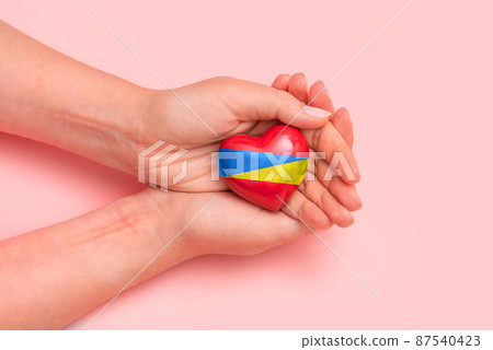 Hand holding a heart with Ukrainian national colors 87540423