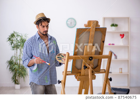 Young man enjoying painting at the studio Young man enjoying painting at the studio 87540675