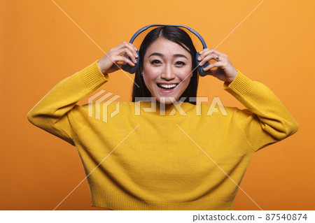 Beautiful smiling heartily woman taking off headphones when she meets her friend. Beautiful smiling heartily woman taking off headphones when she meets her friend. 87540874