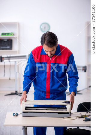 Young male repairman repairing air-conditioner Young male repairman repairing air-conditioner 87541106