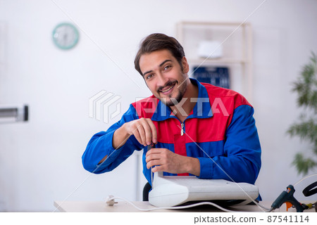 Young male repairman repairing heater Young male repairman repairing heater 87541114