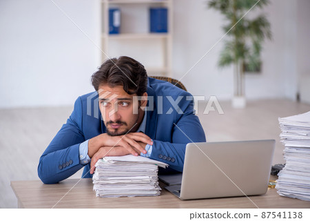 Young male employee and too much work in the office 87541138