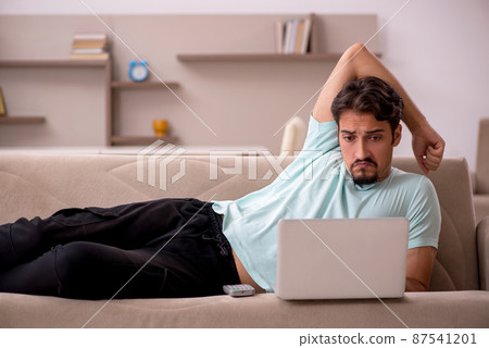 Young man sitting on the sofa with computer at home Young man sitting on the sofa with computer at home 87541201