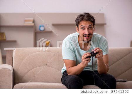 Young man playing joystick games at home Young man playing joystick games at home 87541202