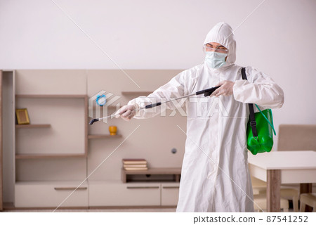 Young male contractor doing pest control at home 87541252