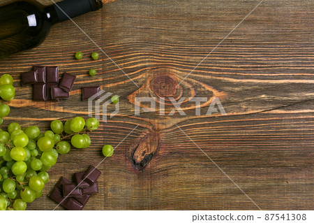 Bottle of wine and ripe grapes on wooden background Bottle of wine and ripe grapes on wooden background 87541308