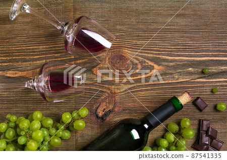 Two glasses, bottle of red wine and grape on a wooden table Two glasses, bottle of red wine and grape on a wooden table 87541335