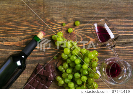 Two glasses, bottle of red wine and grape on a wooden table Two glasses, bottle of red wine and grape on a wooden table 87541419