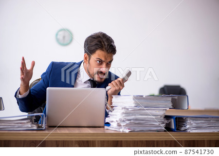 Young male employee and too much work in the office Young male employee and too much work in the office 87541730