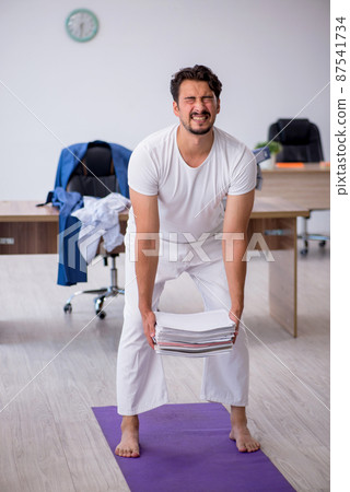 Young male employee doing sport exercises in the office Young male employee doing sport exercises in the office 87541734