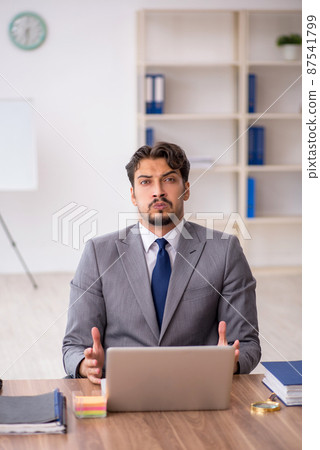 Young male employee sitting in the office Young male employee sitting in the office 87541799